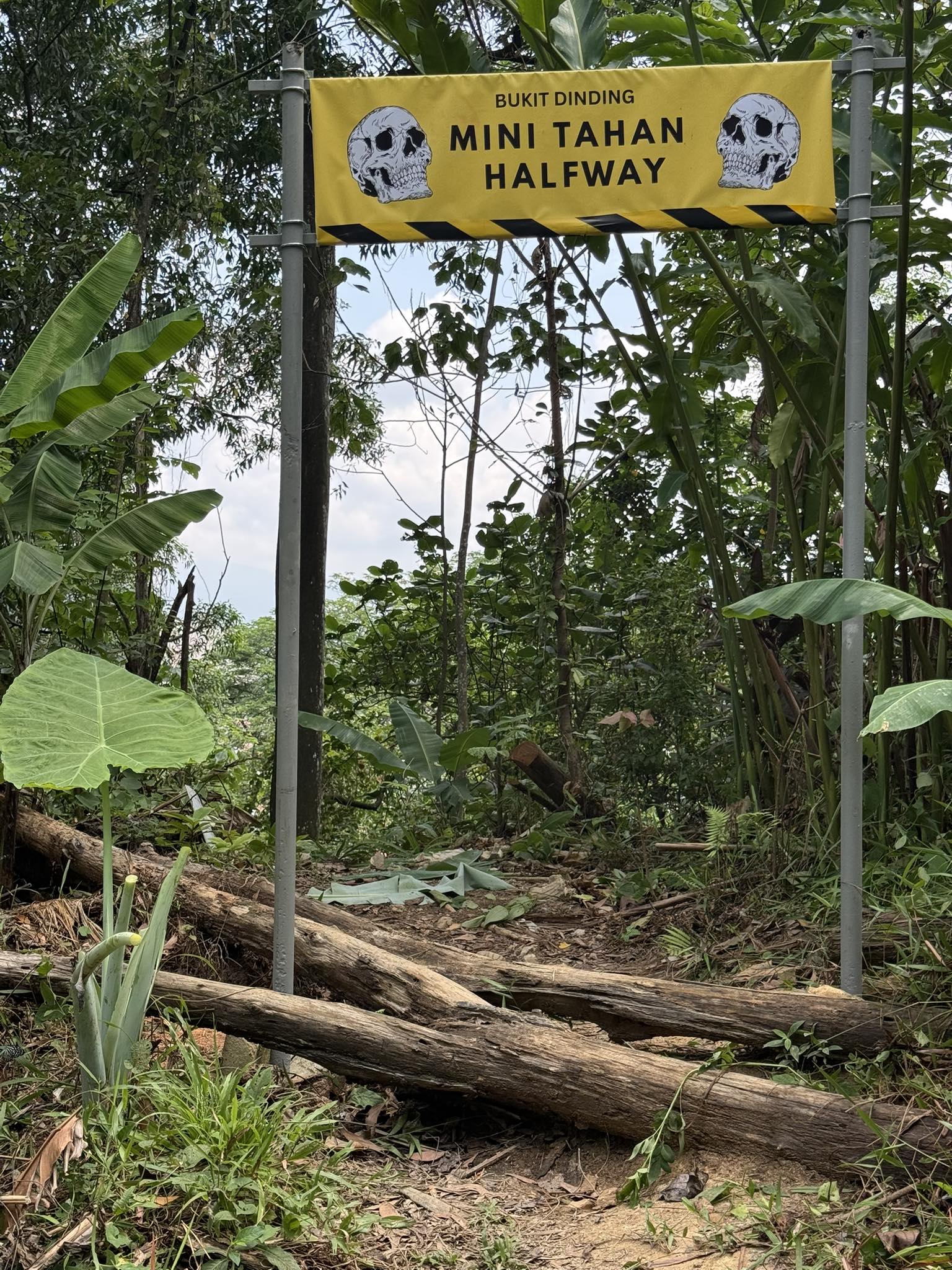 A Mini Tahan Halfway trail sign at Bukit Dinding surrounded by forest.